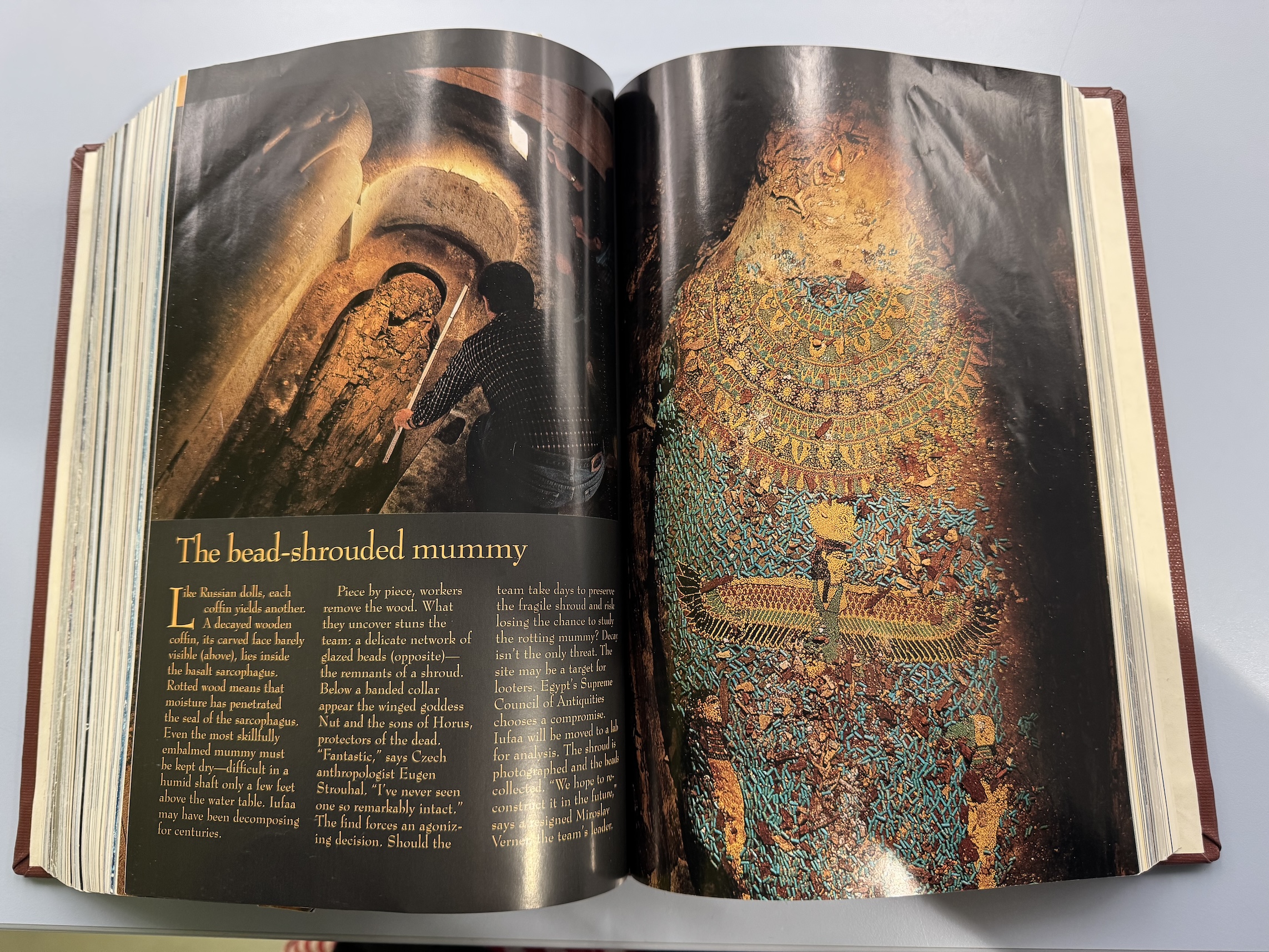 magazine spread, open to a story called Abusir Tomb and showing a mummy in a beaded shroud